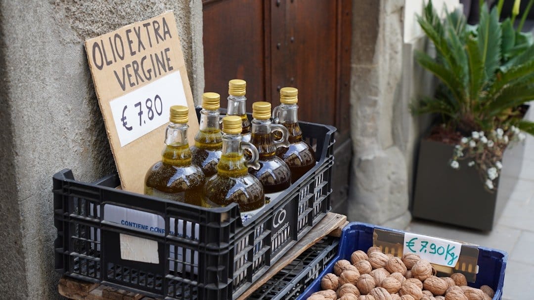 A bottle of Italian extra virgin olive oil on a wooden table, highlighting price tags and olive branches.