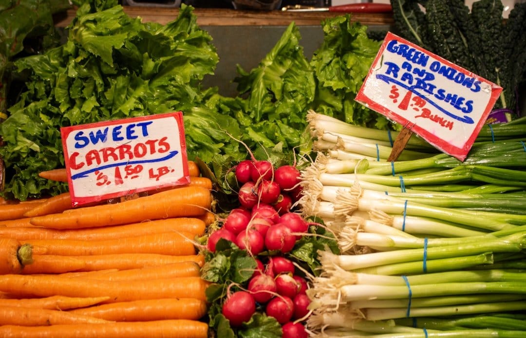 Colorful assortment of seasonal fruits and vegetables displayed on a rustic wooden table, emphasizing fresh, local produce.
