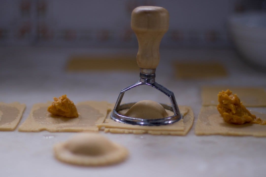 Freshly made pasta dough on a wooden surface, with flour and eggs, showcasing the two-ingredient recipe.