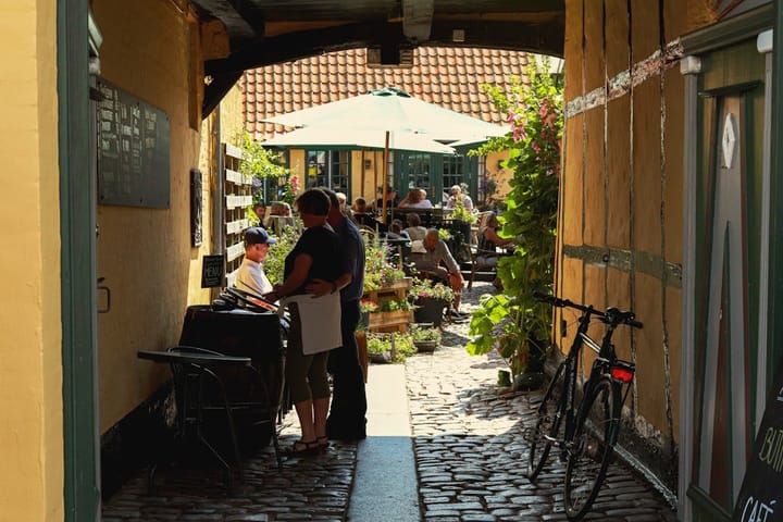 A scenic view of a cozy workspace in a European café, showcasing a laptop, coffee, and vibrant surroundings.