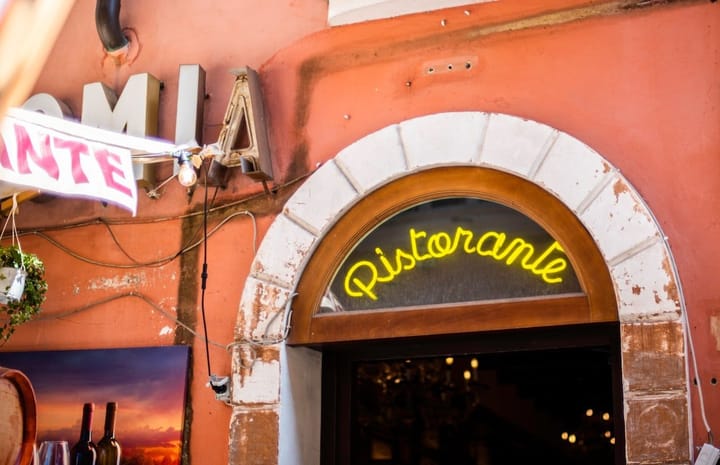 A bustling Rome restaurant with outdoor seating, featuring diners enjoying pasta and wine under colorful awnings.