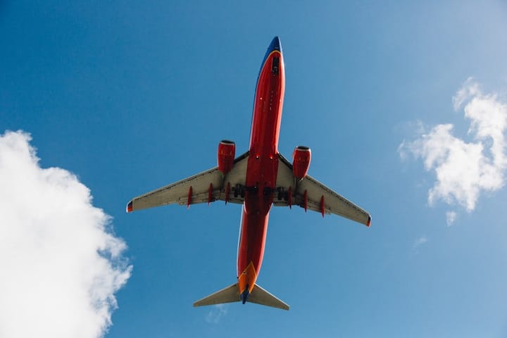 A scenic view of a Norwegian fjord with a budget airline plane flying overhead, highlighting travel and holiday experiences.