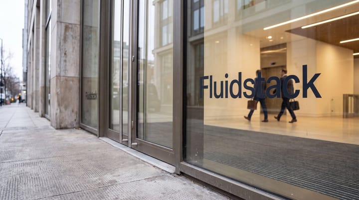 Fluidstack office entrance with glass wordmark, access-controlled doors, and people crossing a bright lobby.