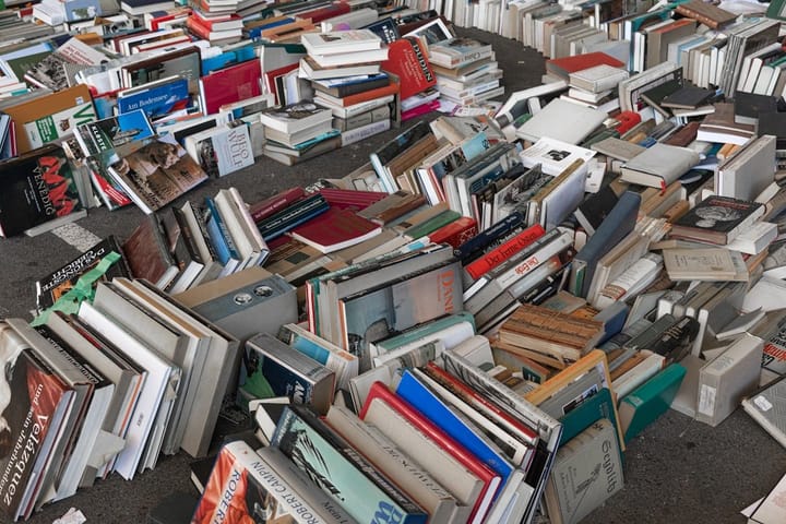 A stack of books with digital devices, symbolizing the clash between traditional literature and modern technology.