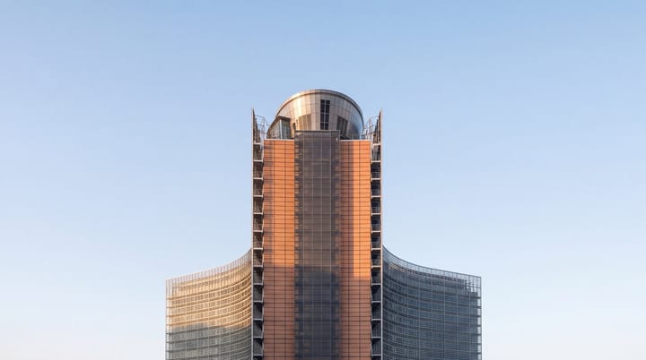 European Commission headquarters rising against a clear blue sky in warm evening light.